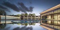 an empty pool on a cloudy day with many buildings reflected in the water, and trees, outside