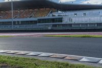 an empty race track with lots of buildings in the background and grass in front of the stand