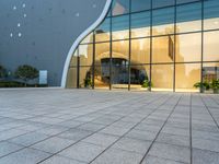 a large glass and steel building that's reflecting the city's sky behind it