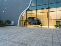 a large glass and steel building that's reflecting the city's sky behind it