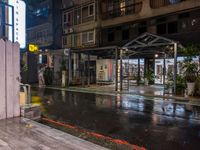 an outside restaurant on a rainy day with a neon sign, lights and benches in the rain