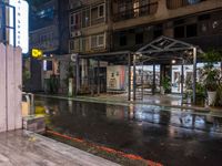 an outside restaurant on a rainy day with a neon sign, lights and benches in the rain