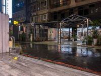 an outside restaurant on a rainy day with a neon sign, lights and benches in the rain