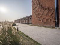 a walkway leading to some tall brick buildings near a lake and grassy land in the background