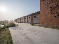 a walkway leading to some tall brick buildings near a lake and grassy land in the background