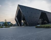 the building that is designed to be as black as possible in a city, looks like it's leaning on a face