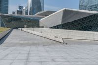 man skateboarding on a paved walkway leading to a large building with a sloping, geometric pattern