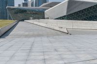 man skateboarding on a paved walkway leading to a large building with a sloping, geometric pattern