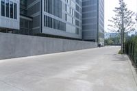 an empty walkway leading to a building complex with many windows and a wall along the street