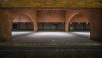 there are two long red brick arches at the end of this walkway that leads to a large room