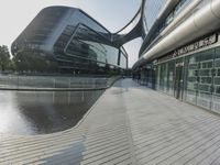 a walkway with many buildings by the water on it next to a building with many windows