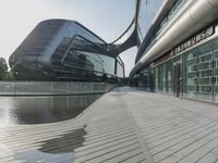 a walkway with many buildings by the water on it next to a building with many windows