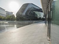 a walkway with many buildings by the water on it next to a building with many windows