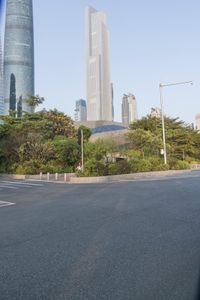 a view of a street, with skyscrapers in the background and a man riding his bike