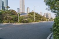 a view of a street, with skyscrapers in the background and a man riding his bike