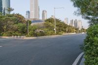 a view of a street, with skyscrapers in the background and a man riding his bike