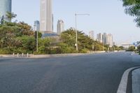 a view of a street, with skyscrapers in the background and a man riding his bike