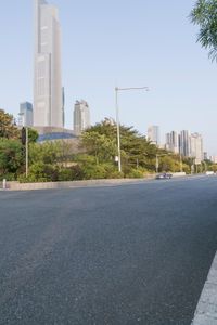 a view of a street, with skyscrapers in the background and a man riding his bike