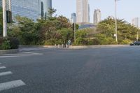 a view of a street, with skyscrapers in the background and a man riding his bike