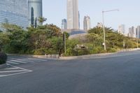 a view of a street, with skyscrapers in the background and a man riding his bike