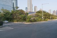 a view of a street, with skyscrapers in the background and a man riding his bike