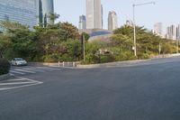 a view of a street, with skyscrapers in the background and a man riding his bike