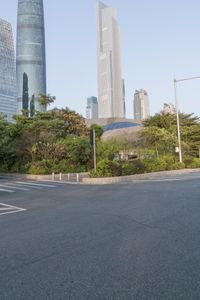 a view of a street, with skyscrapers in the background and a man riding his bike