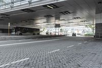 a street with parking spaces and white bricks in the floor near by a large building