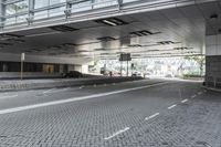 a street with parking spaces and white bricks in the floor near by a large building