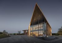 a building with glass windows and a big triangle on the top of the building at twilight