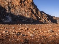 a person on a dirt trail walking by a steep, rocky cliff side near water