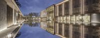 the large building has a beautiful reflection in it's water way at night time