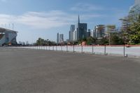 a parking lot with tall buildings in the background with red fences on it and a sky scraper to the side