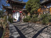 a building with several chinese archways above the gate that leads up to it and a stream below