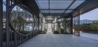 a long walkway leading into a building on concrete tiles underneath a canopy that has a circular design