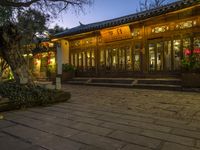 the outside of a chinese building with some lights on at dusk's time or night