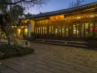 the outside of a chinese building with some lights on at dusk's time or night