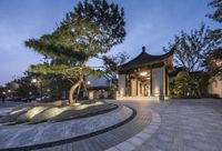 a park and some trees in a city at night near a building with a chinese style dome