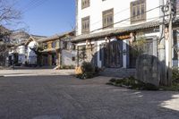 a street with stone walls lined in chinese writing and flowers and vines around the windows