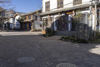 a street with stone walls lined in chinese writing and flowers and vines around the windows