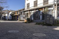 a street with stone walls lined in chinese writing and flowers and vines around the windows