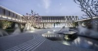 there is water gusping from the fountain into the courtyard area of the building at dusk