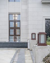 a sidewalk with steps leading to the side and glass doors to a large window on a building with a lot of grass