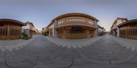 a large circular driveway with several wooden buildings in the background and on top is a wooden house