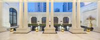 columns and columns in a building with windows overlooking a fountain in a courtyard area and several urns along the walkway