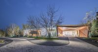 a small concrete park is surrounded by grass, rocks and trees at night with lights on