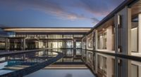 a beautiful looking pool inside of a large building at dusk time, with reflectioning in it