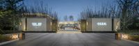 a courtyard that has a large wall of white boxes and lights on the outside, with trees and bushes behind it