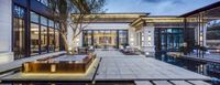 an indoor lobby with stone and wood seating and outdoor pool at night with modern architecture