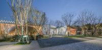 the outside of a building that has an open area with stone patios and trees on either side